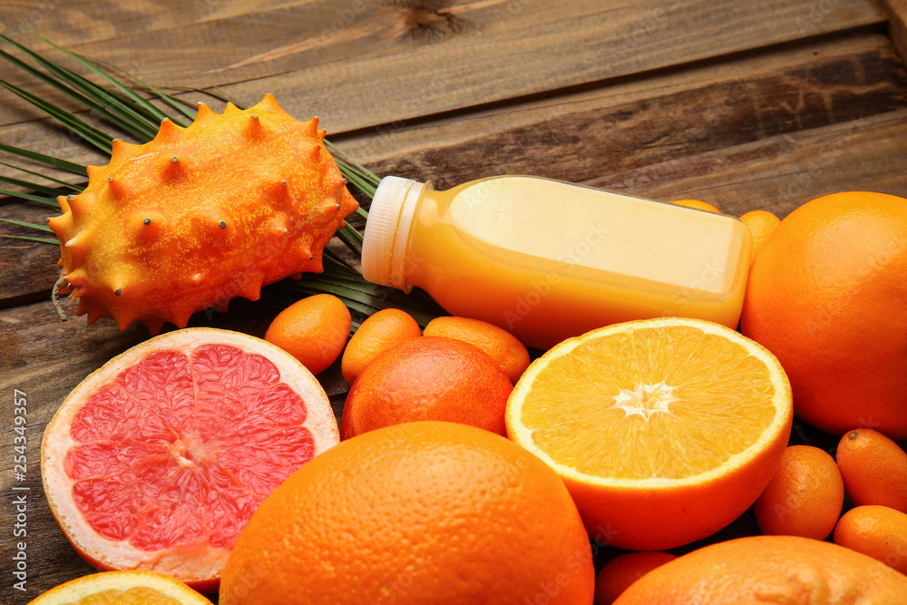 Assortment of tasty exotic fruits with bottle of juice on wooden background