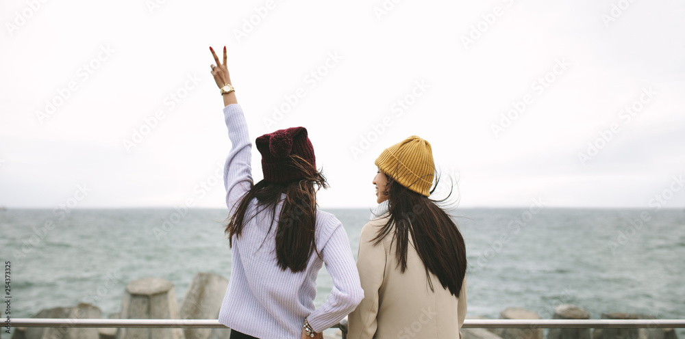 Rear view of two women standing together outdoors