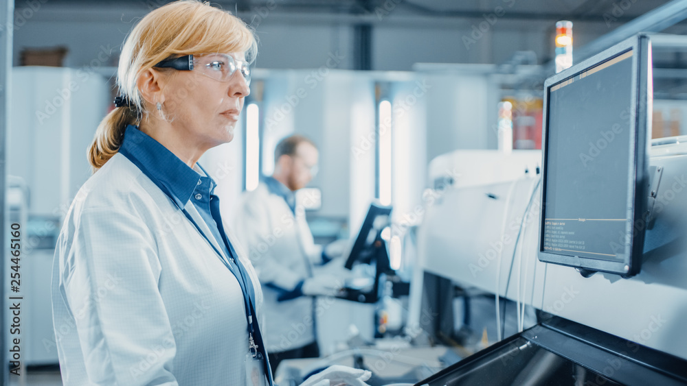 Portrait Shot of a Female Engineer On High Tech Factory Uses Computer for Programing Pick and Place 