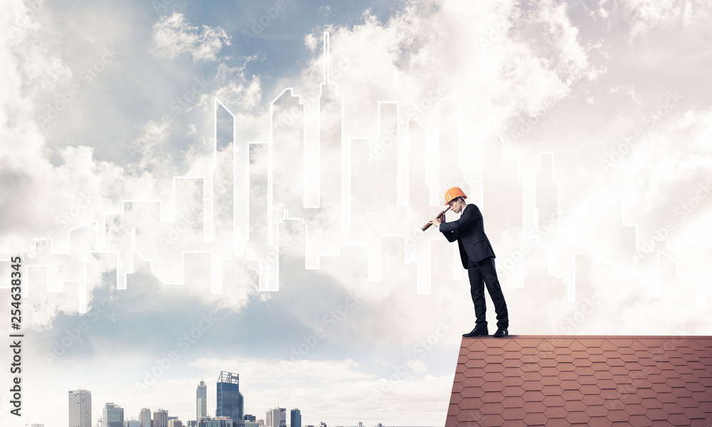 Engineer man standing on roof and looking in spyglass. Mixed med