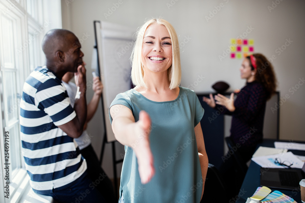 Welcoming young designer standing in an office extending a hands