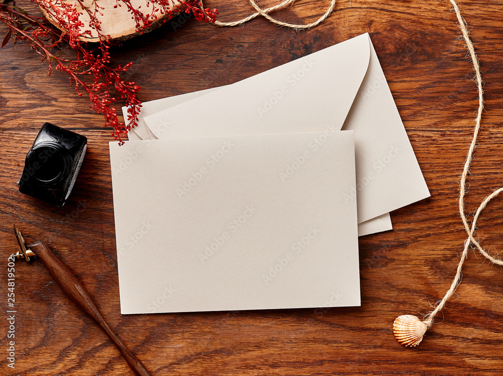 Mock up of blank envelopes on wooden background with calligraphy pen and ink. View from the top.