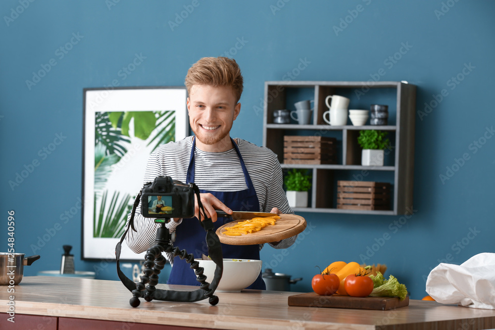 Young male food blogger recording video in kitchen