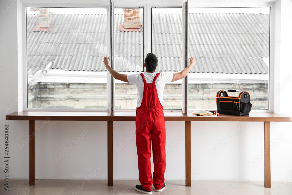 Young worker checking window after repair