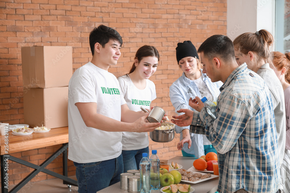 Young volunteers giving food to poor people