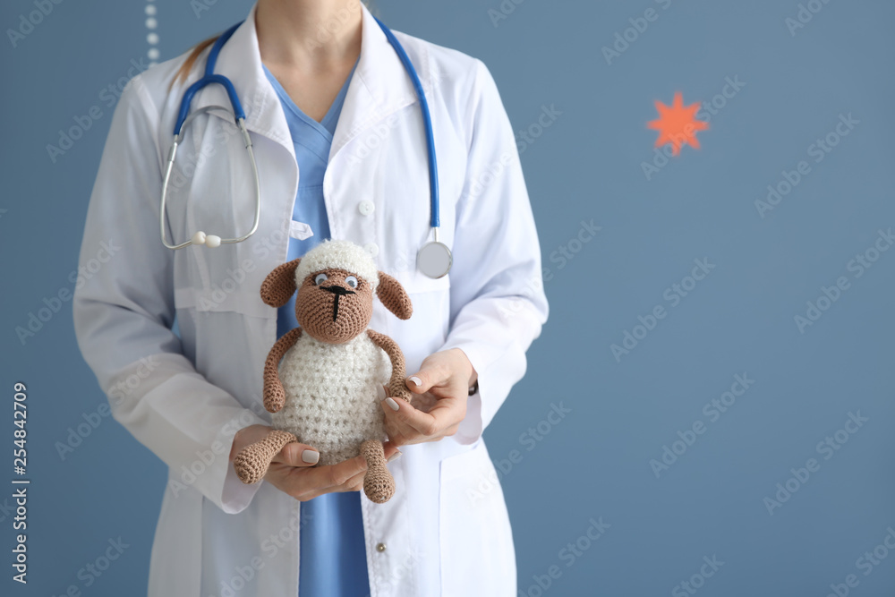 Pediatrician with toy on color background