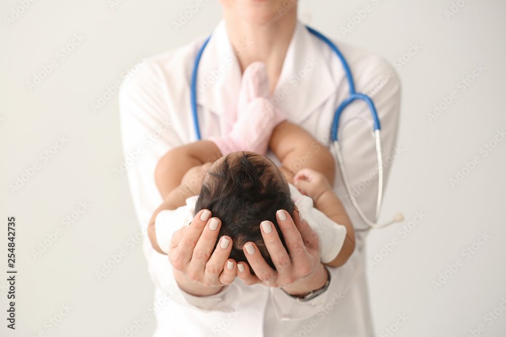 Pediatrician with African-American baby on light background