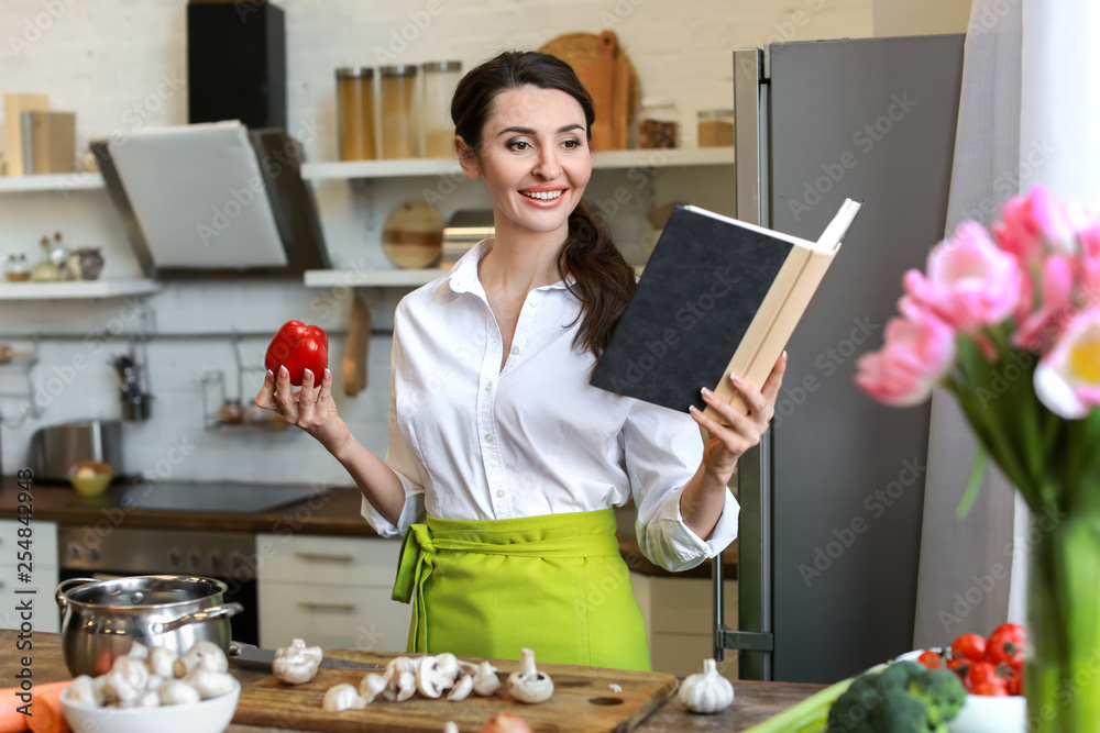 Beautiful woman reading new recipes in kitchen at home