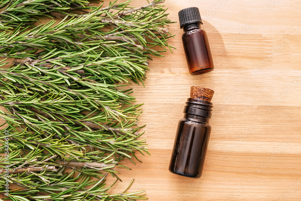 Bottles of oil and fresh rosemary on wooden table