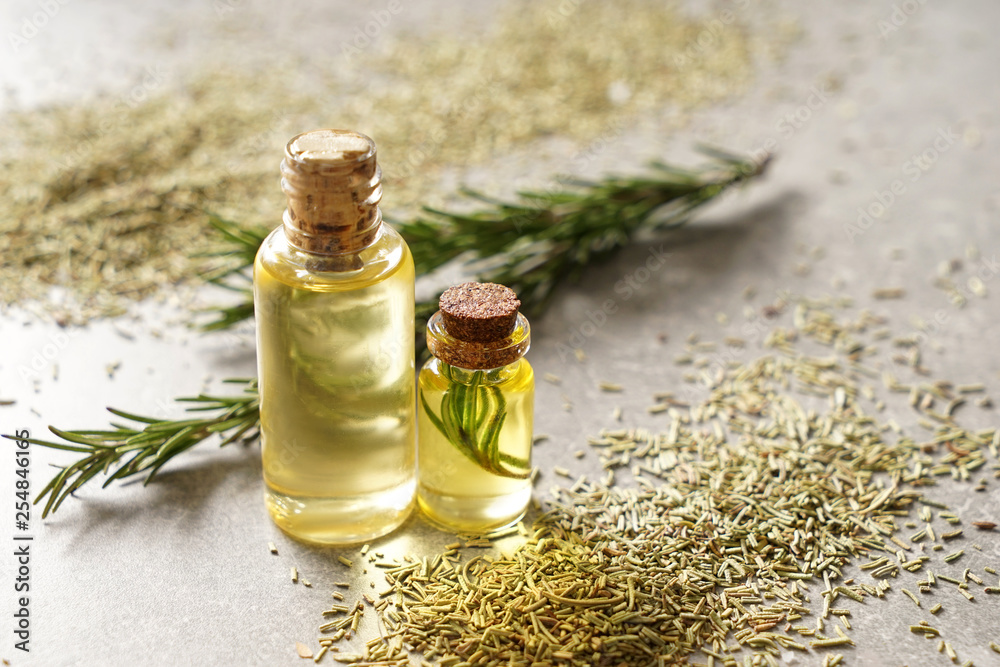 Bottles of rosemary oil on grey table