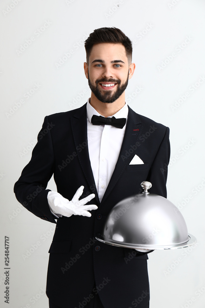 Waiter with tray and cloche on light background