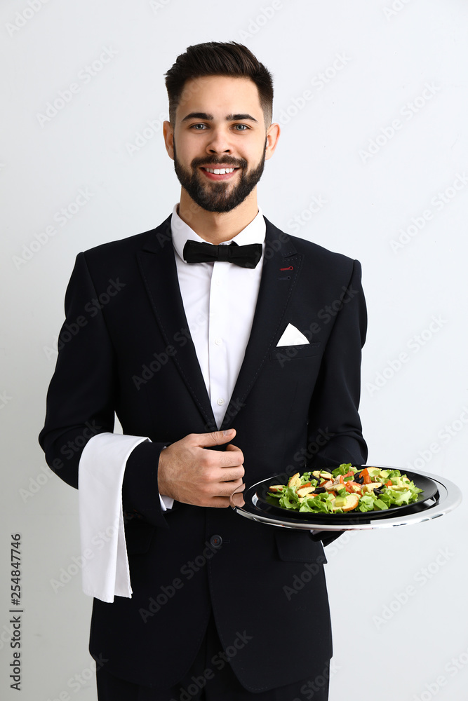 Waiter with fresh salad on light background