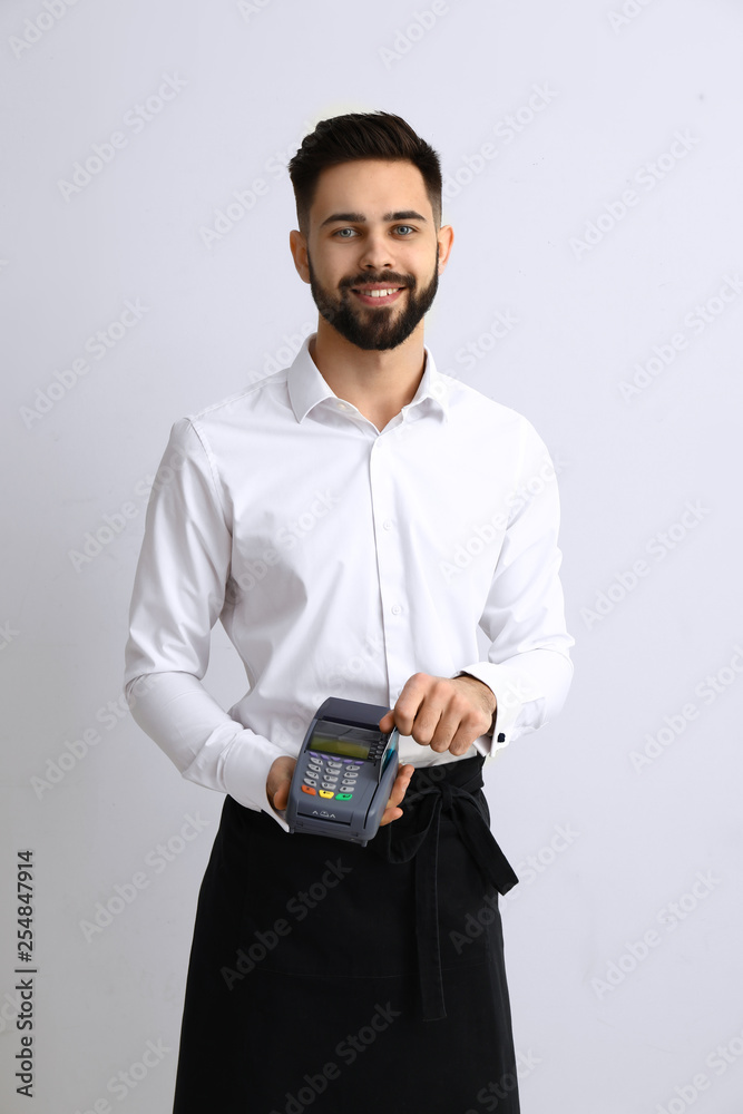 Waiter with payment terminal on light background