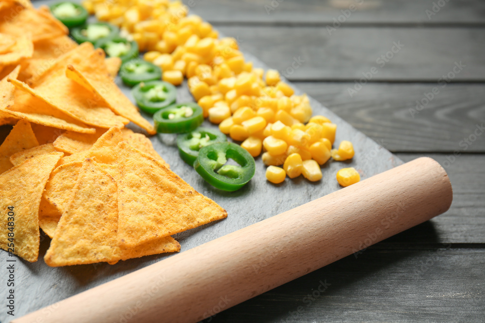 Stand with tasty nachos, jalapeno and corn on table