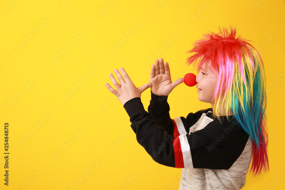 Funny little boy with clown nose and wig on color background. April fools day celebration