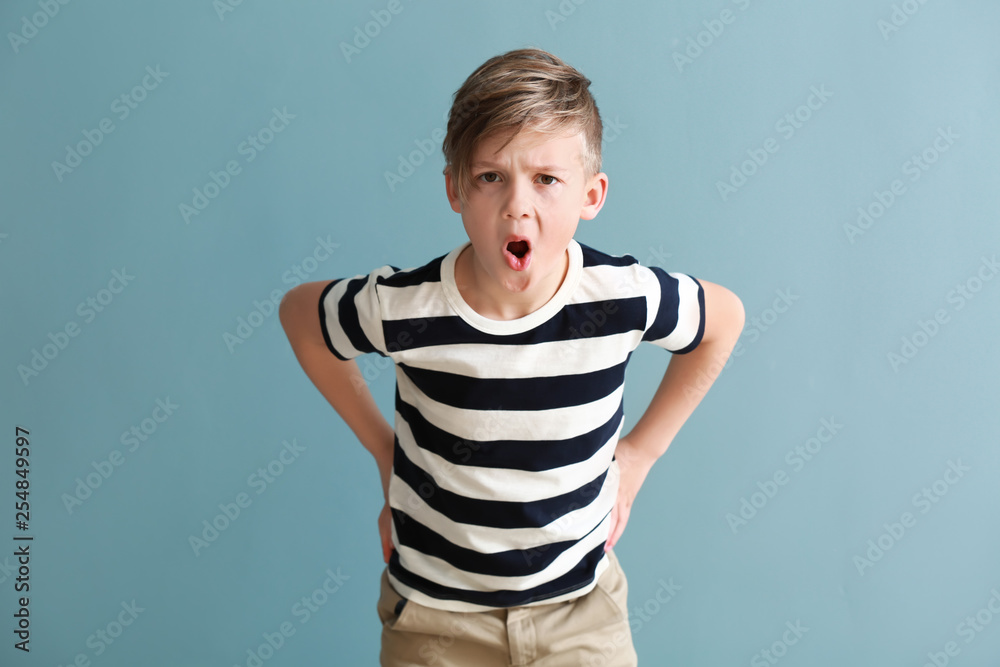 Displeased little boy on color background