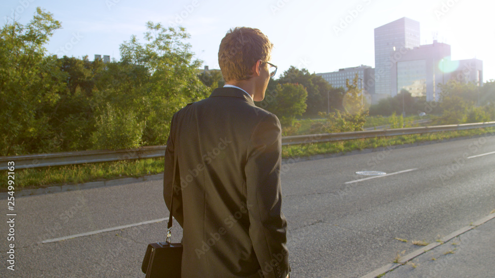 CLOSE UP: Young man in a black suit casually walking to a business meeting.