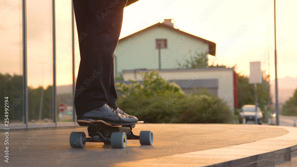 CLOSE UP: Unrecognizable yuppie going home from work on his electric skateboard