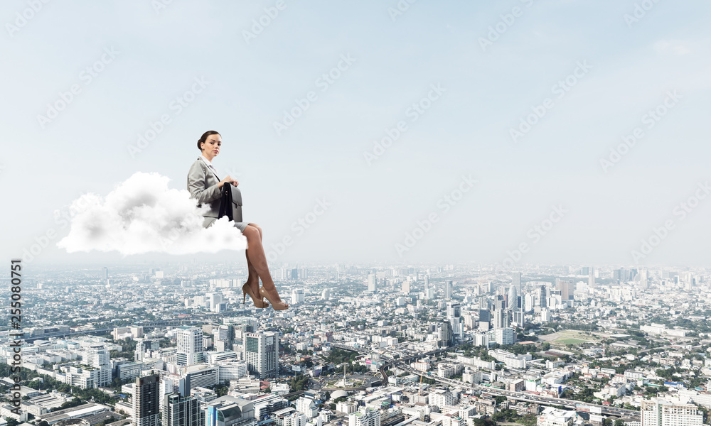 Businesswoman or accountant on cloud floating high above modern city