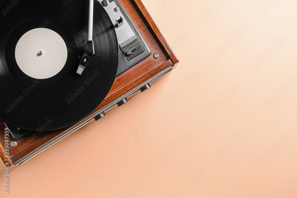 Record player with vinyl disc on color background