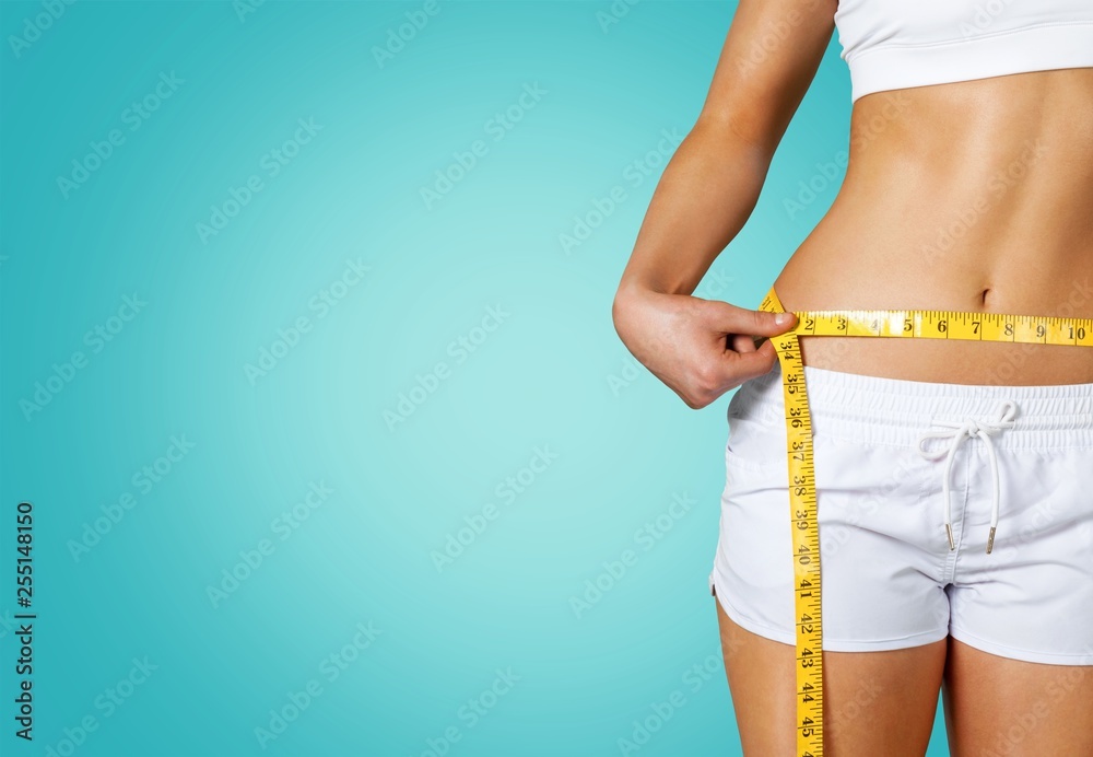 Slim young woman measuring her thin waist