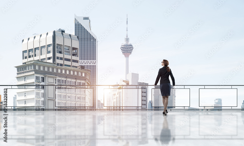 Sunrise above skyscrapers and businesswoman facing new day