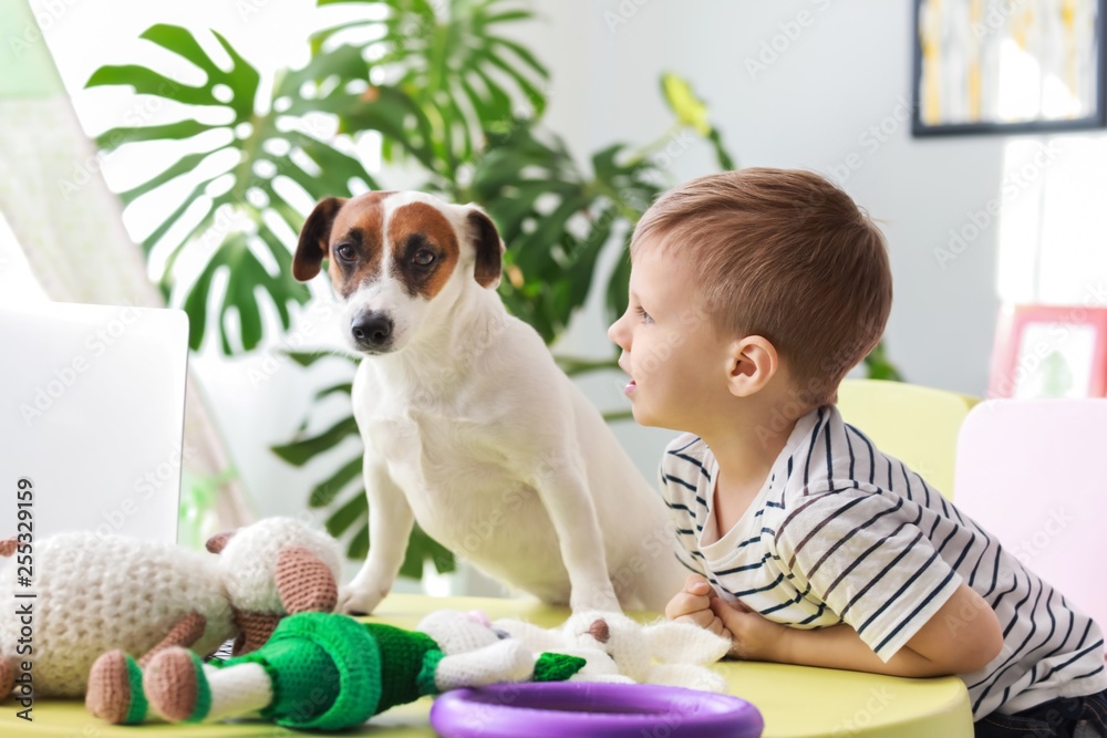 Cute little boy with funny dog at home