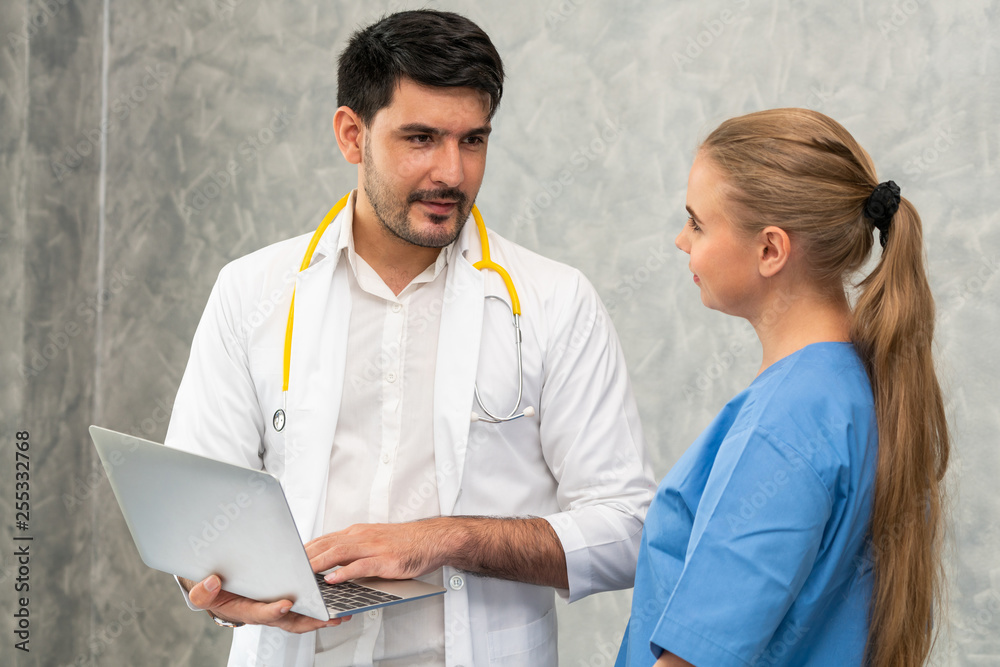 Happy doctor and nurse working with laptop computer in hospital office. Healthcare and medical conce