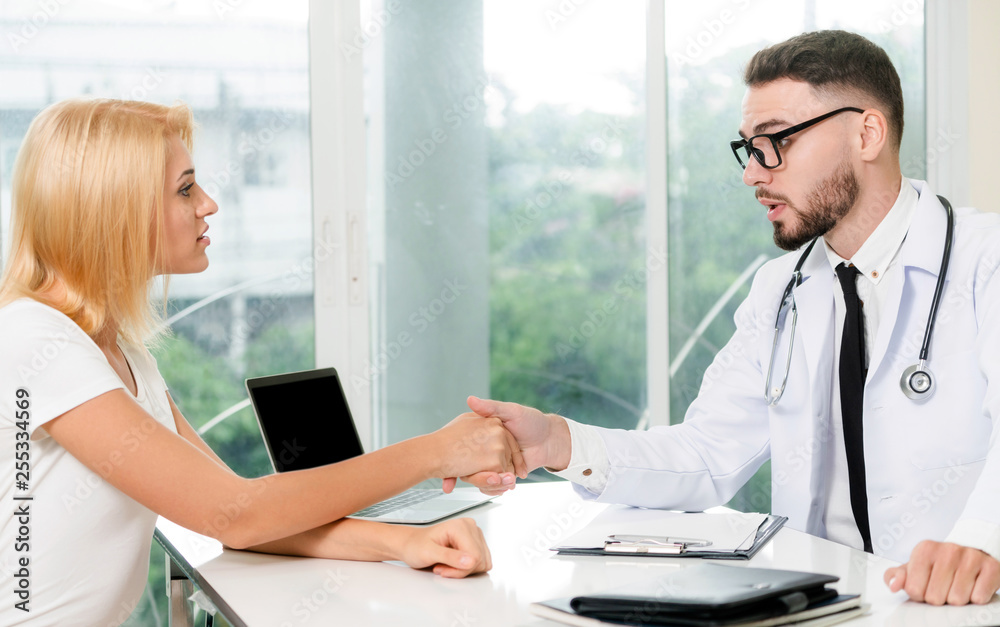 Male doctor is talking to female patient in hospital office. Healthcare and medical service.