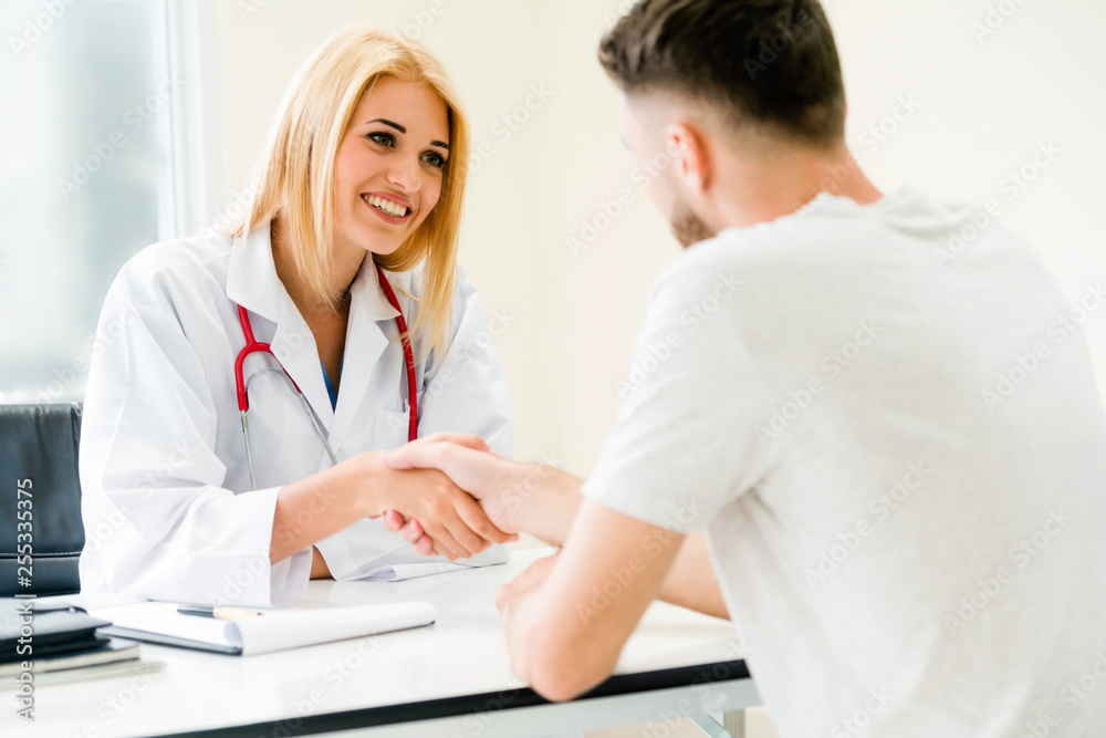 Woman doctor doing handshake with male patient in hospital office room. Healthcare and medical servi