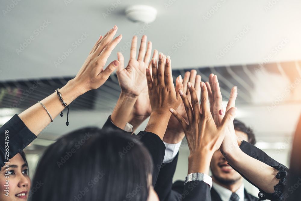 Many happy business people raise hands together with joy and success. Company employee celebrate aft