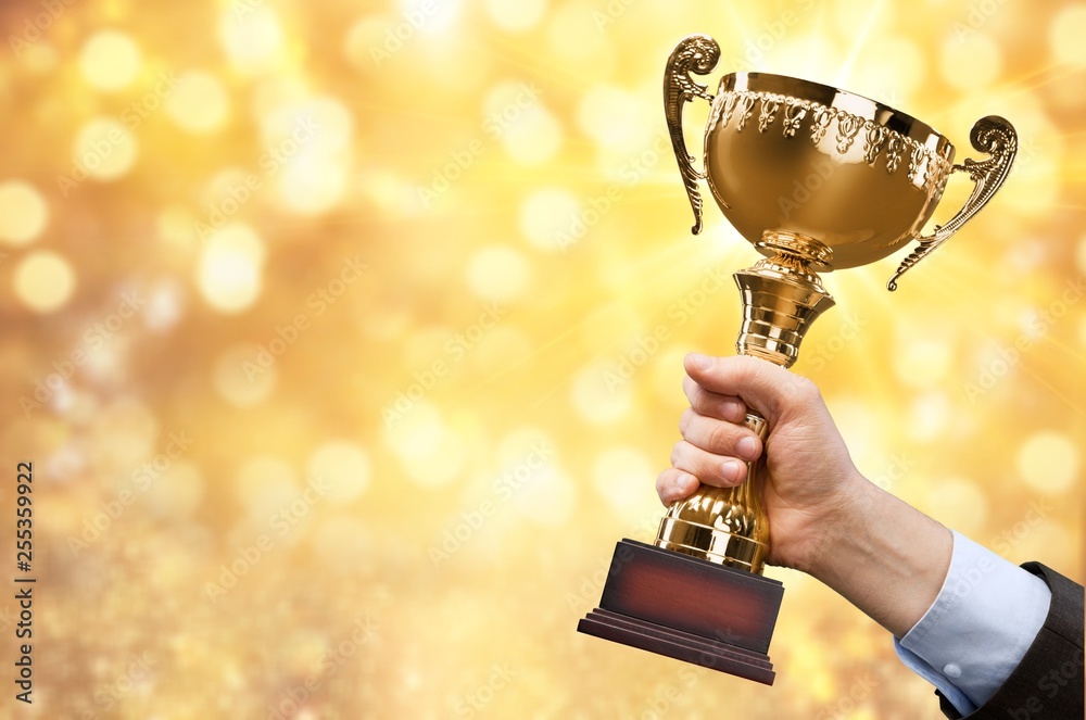 Hands holding golden trophy on background