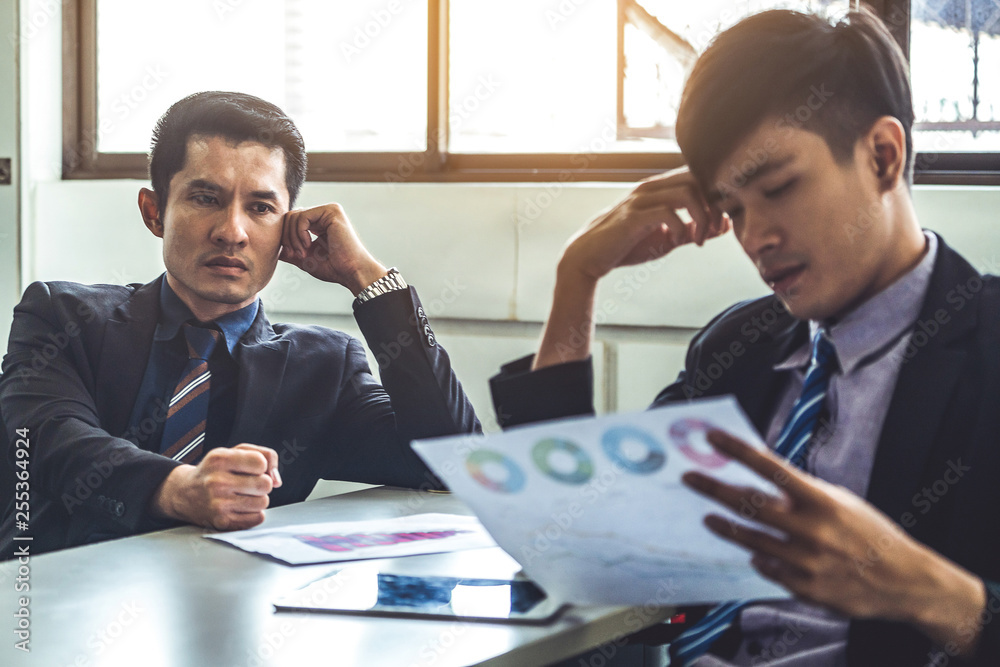 Unhappy business manager and young businessman partner in meeting room at the office. They are under