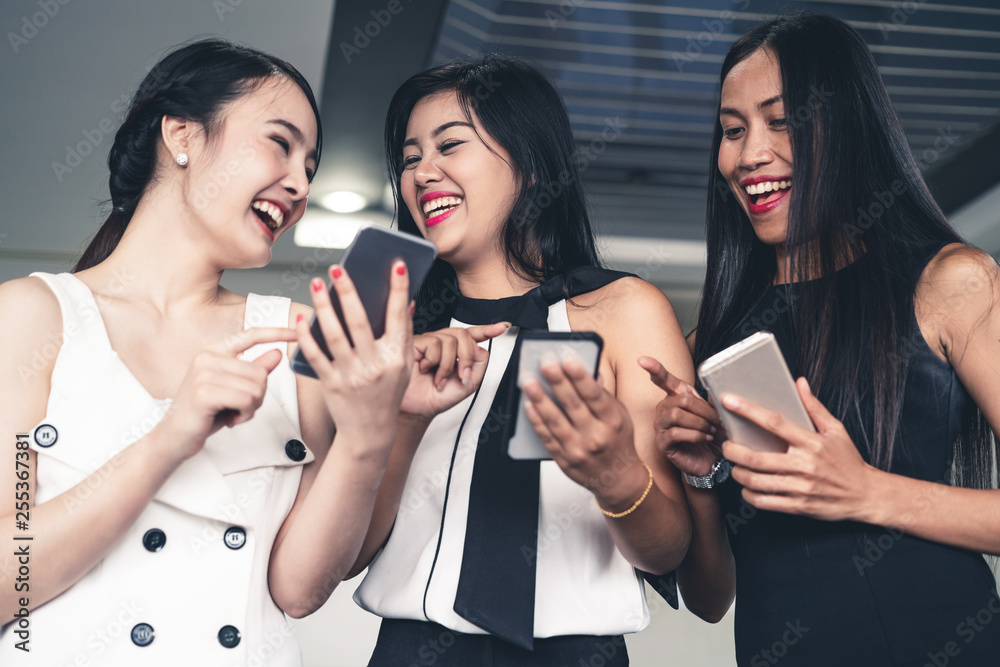 Three women friends having conversation while looking at mobile phone in their hands. Concept of soc