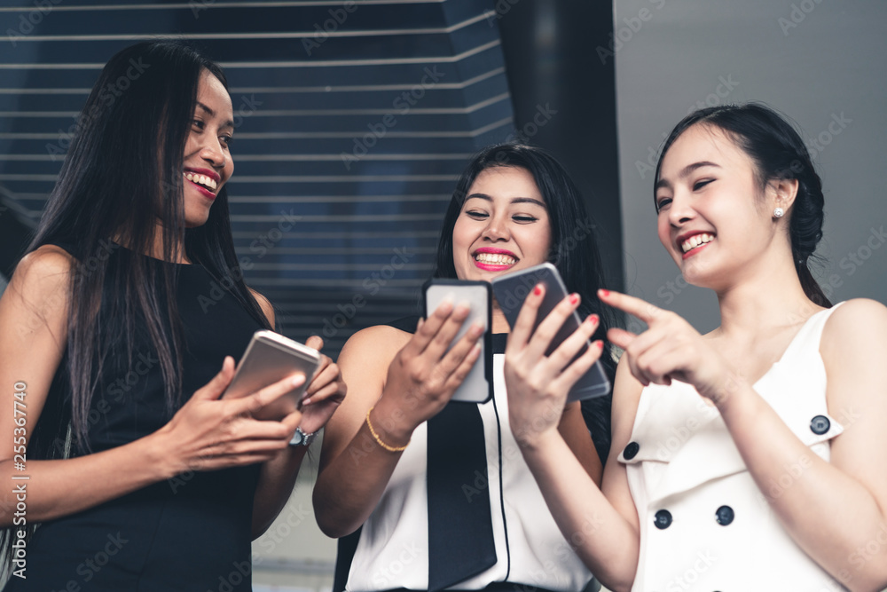 Three women friends having conversation while looking at mobile phone in their hands. Concept of soc