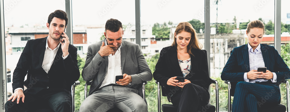 女商人和商人在办公室椅子上等待面试时使用手机