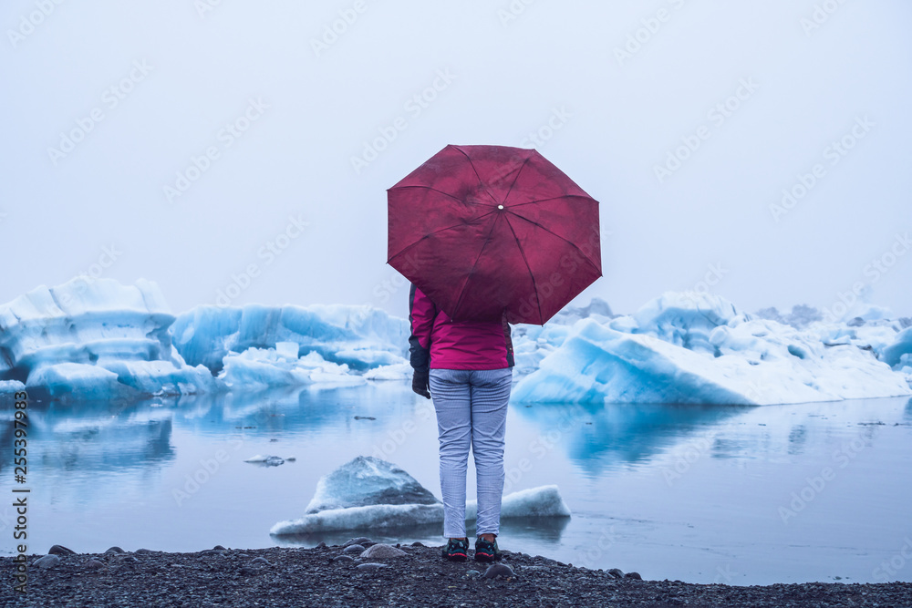 Woman traveler travels to Jokulsarlon beautiful glacial lagoon in Iceland. Jokulsarlon is a famous d