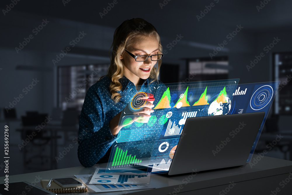 Beautiful blonde working on laptop and infographs out of screen. Mixed media