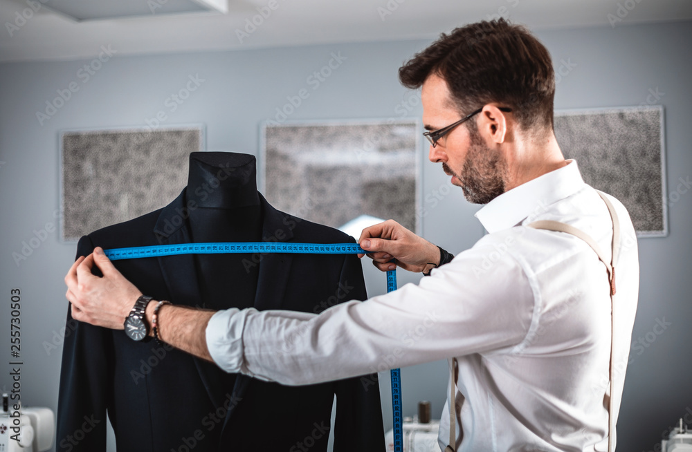 Tailor measuring jacket suit on mannequin at fashion design workshop