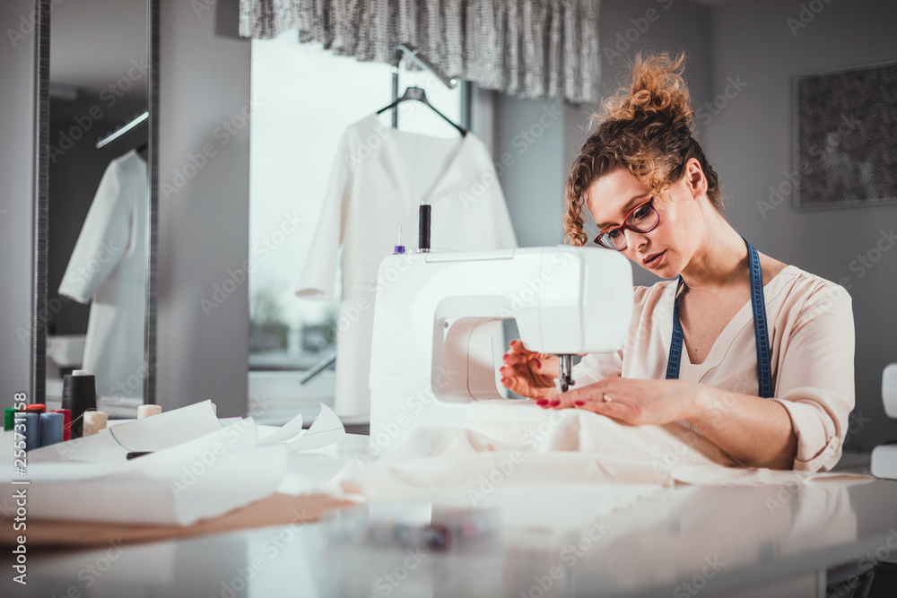 Tailor during work using sewing machine, fashion designer at workshop