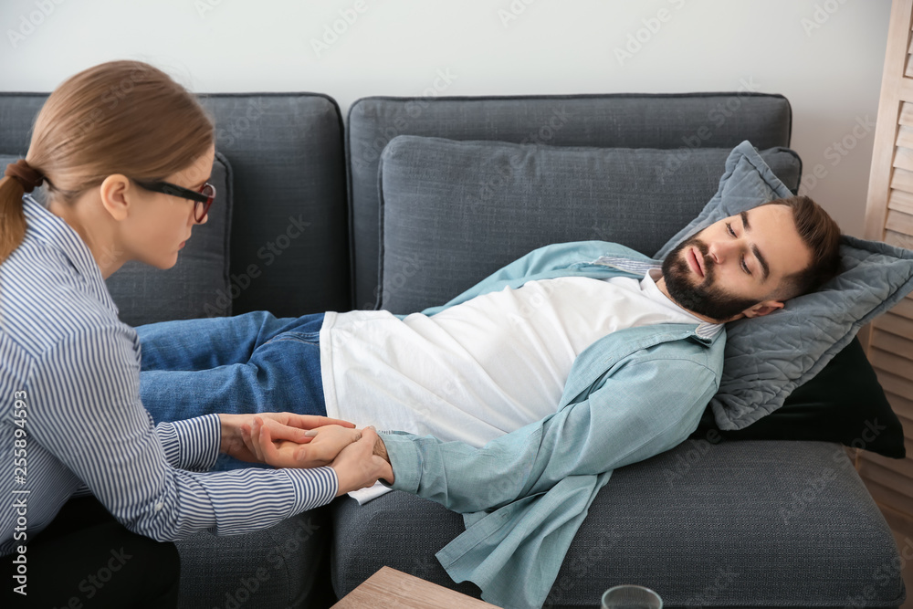 Female psychologist working with patient lying on sofa in her office