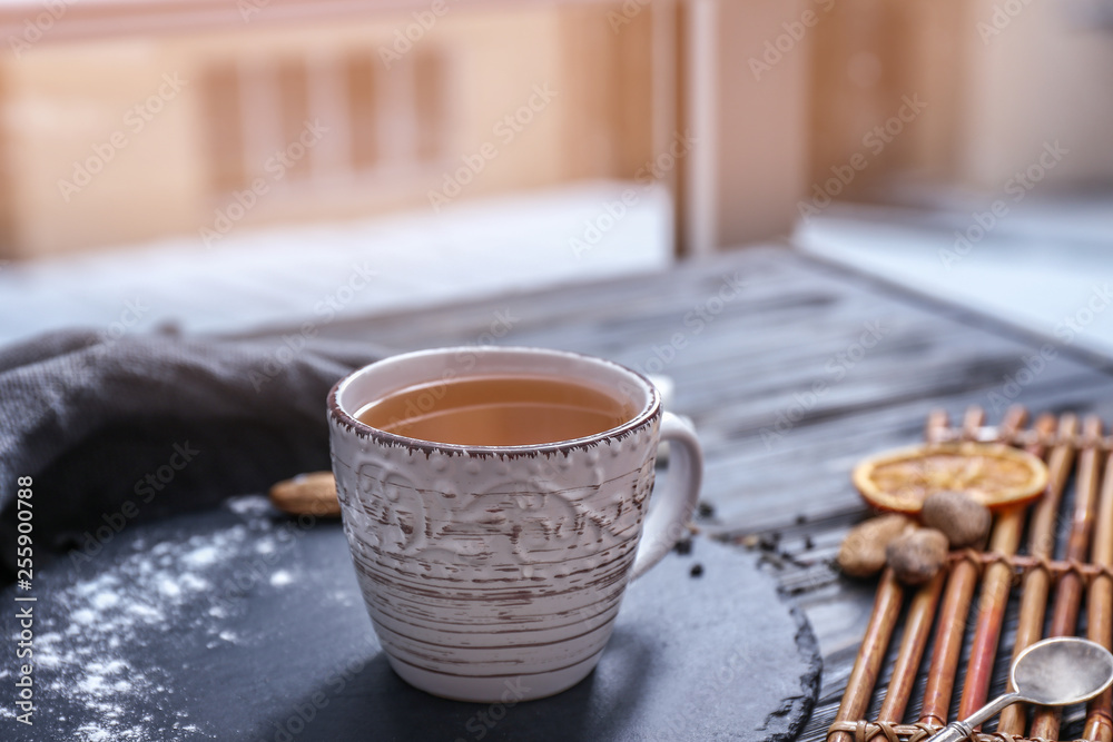 一杯热茶放在靠近窗户的木桌上