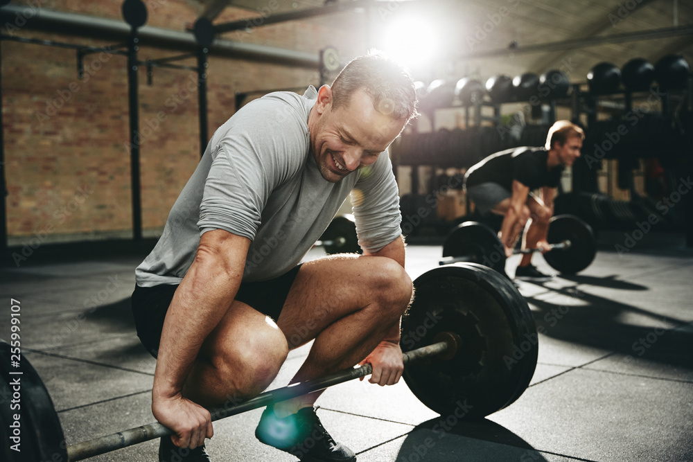 Fit man trying to lift weights at the gym