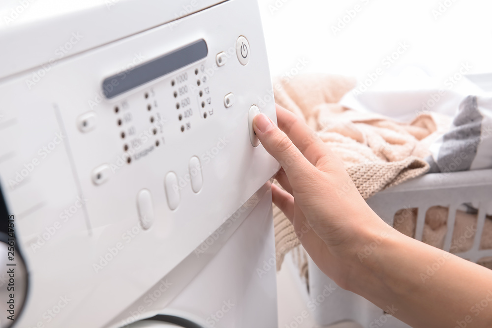 Woman switching on washing machine, closeup