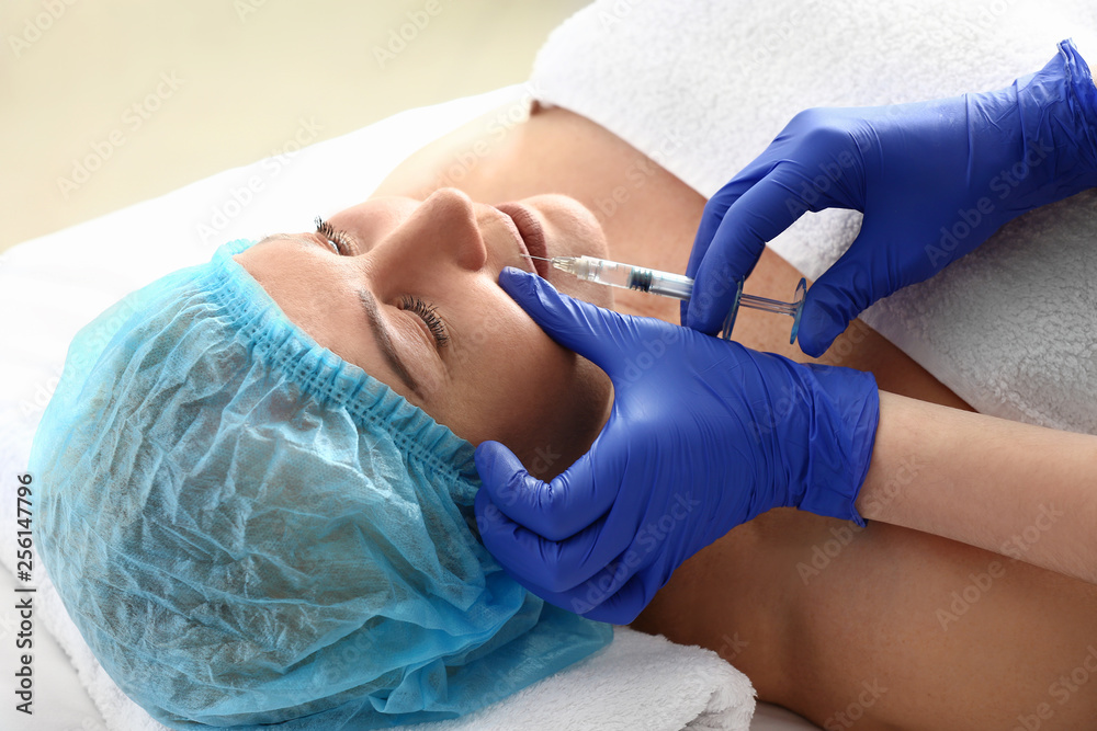 Mature woman receiving filler injection in beauty salon