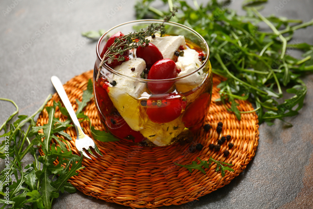 Glass jar with tasty feta cheese in olive oil on table