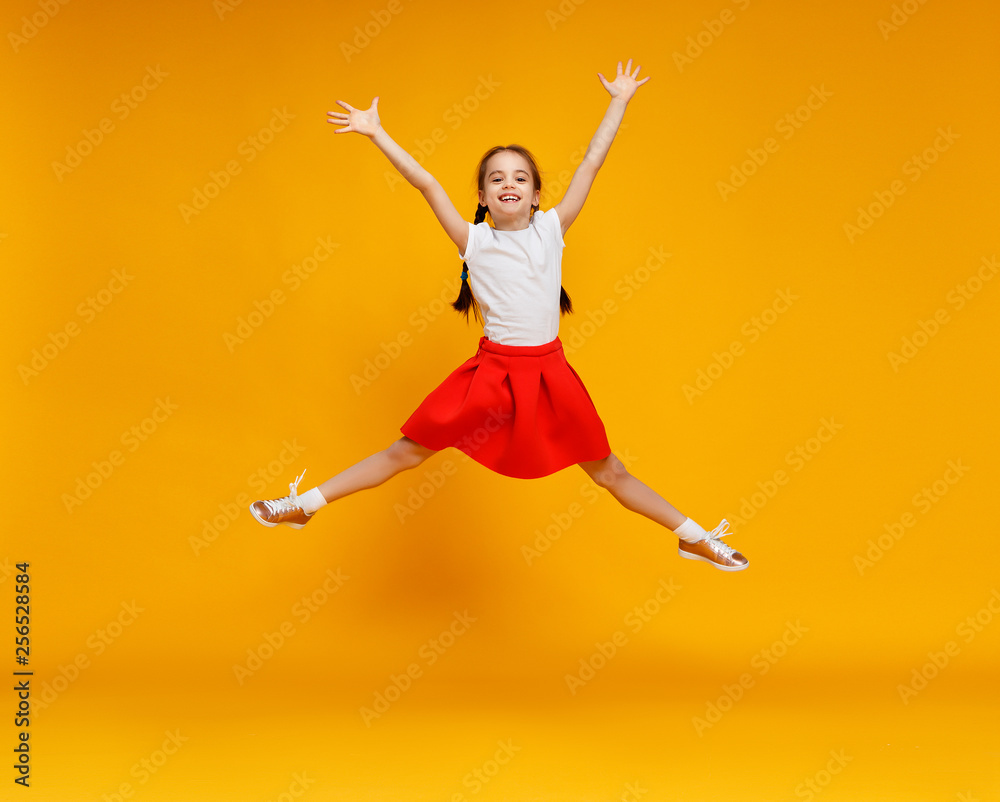 funny child girl jumping on colored yellow background.