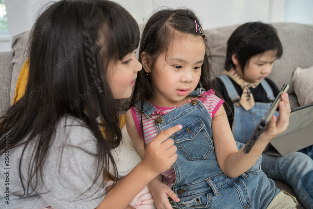 一群小孩子一起在数字平板电脑和手机上观看电影、电影和动画片。孩子们在玩