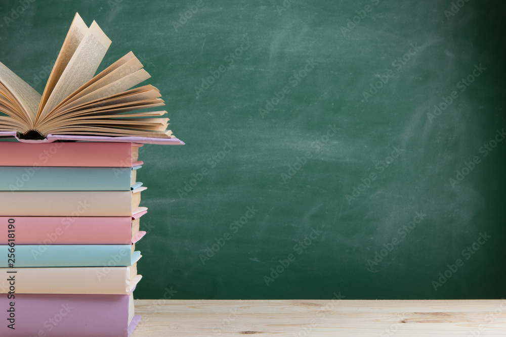 Education and reading concept - group of colorful books on the wooden table in the classroom, blackb