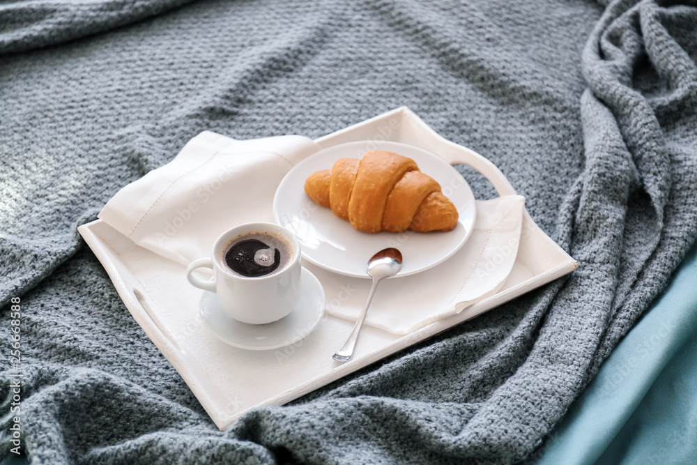 Tray with tasty breakfast on bed